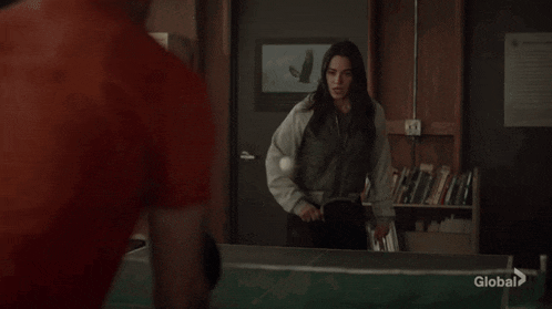 a man in a red t-shirt is playing ping pong