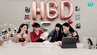 a group of girls are sitting at a table with balloons that spell out hbd