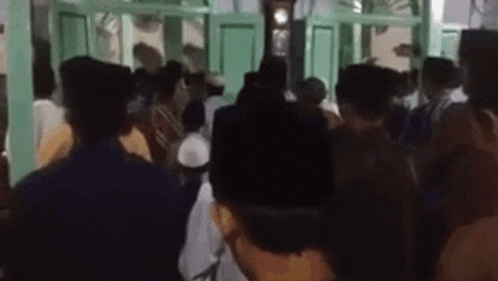 a group of people are standing in a room in a mosque .