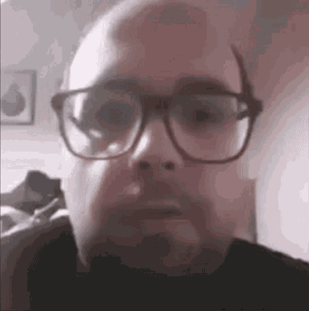 a man wearing glasses and a beard is making a funny face .