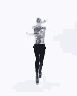 a man with silver paint on his body is dancing in a white room .