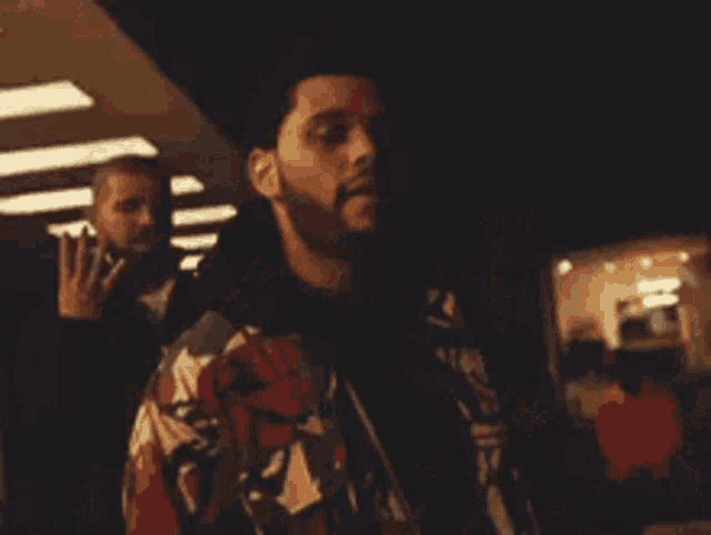 a man with a beard is talking on a cell phone while wearing a camouflage jacket .