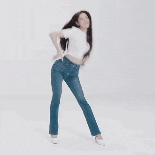 a woman in a white shirt and blue jeans is dancing in a white room .