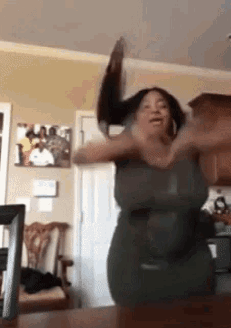 a woman in a green dress is dancing in a room