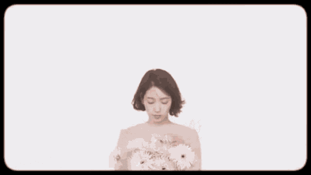 a woman is holding a flower in her mouth and looking at the camera .