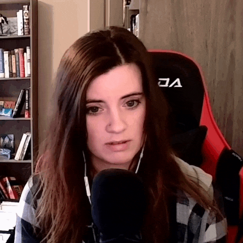 a woman in a plaid shirt is sitting in front of a microphone with a red chair in the background .
