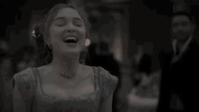 a woman in a blue dress and necklace is smiling