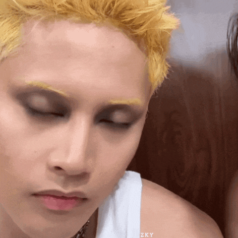a man with yellow hair is wearing a white tank top with zky written on the shoulder