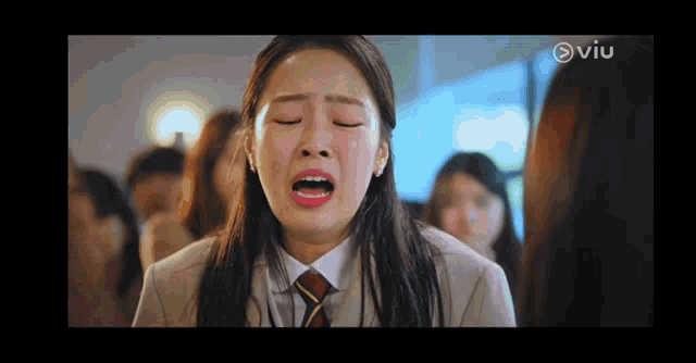 a woman in a suit and tie is crying in front of a crowd .
