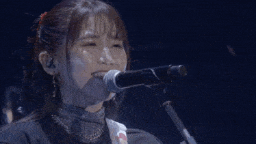 a woman singing into a microphone with a guitar in her hand