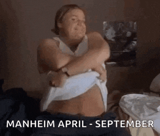 a woman is taking off her shirt while sitting on a bed in a bedroom .