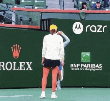 a tennis player stands in front of a rolex and bnp paribas sign