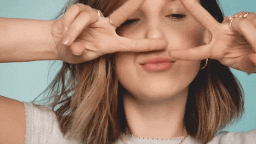 a woman makes a peace sign with her hands
