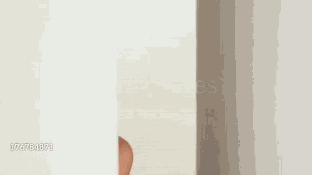 a woman is peeking out of a hole in a wall and making a funny face .