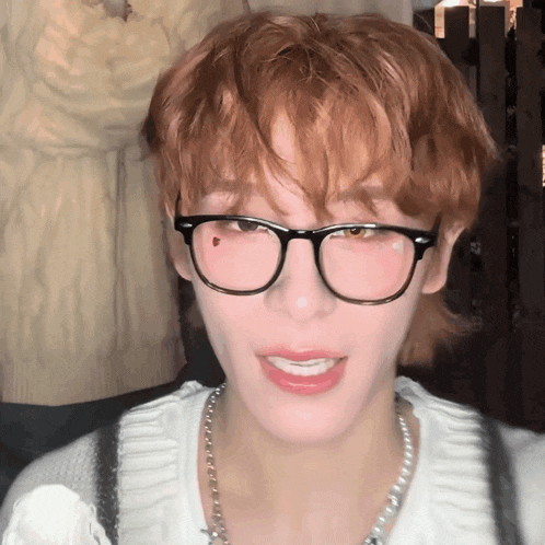 a young man wearing glasses and a pearl necklace