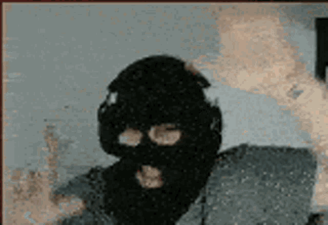 a man wearing a ski mask and headphones giving the middle finger