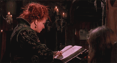 a woman with red hair is reading a book in a dark room with candles