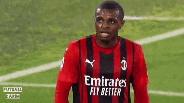 a soccer player wearing an emirates fly better jersey stands on the field