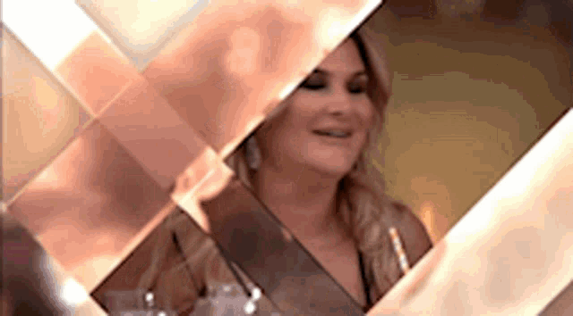 a woman is sitting in front of a mirror looking at herself and smiling .