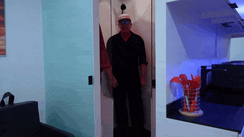 a man wearing a hat that says donald trump stands in a doorway