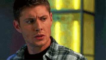 a man wearing a plaid shirt looks at the camera
