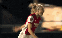 a female soccer player wearing a red emirates jersey is celebrating a goal