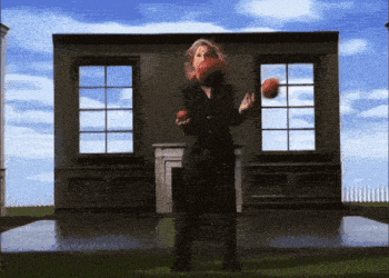a woman in a black suit stands in front of a building holding an apple