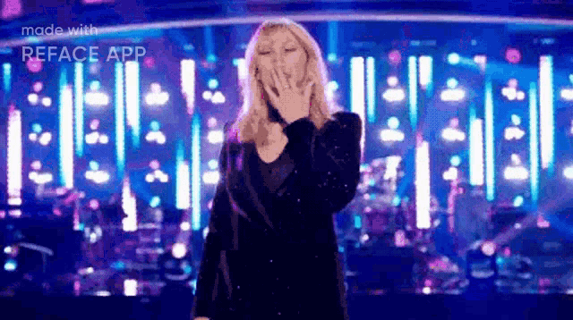 a woman is blowing a kiss while standing on a stage in front of a crowd .