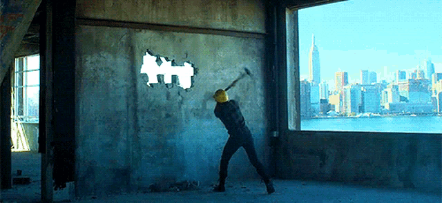 a man is swinging a hammer at a hole in a wall with a city skyline in the background