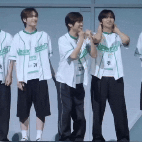 a group of young men wearing baseball jerseys are standing next to each other and laughing .