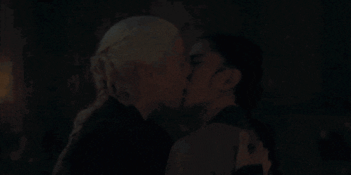a man and woman kissing in a dark room with candles