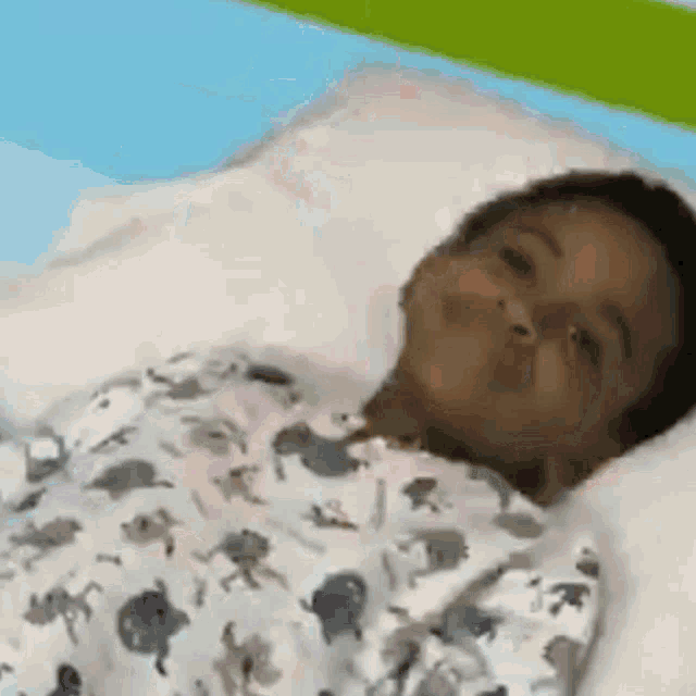 a child is laying in a hospital bed with a pillow and a blanket .