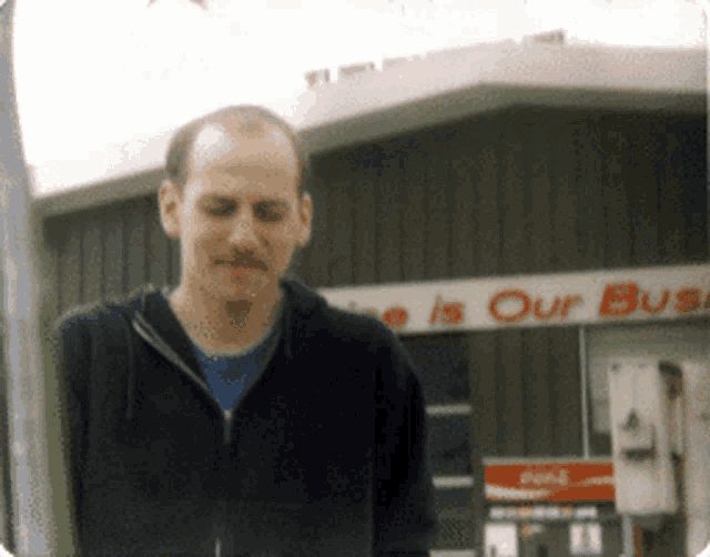 a man stands in front of a building that says ' e is our bus '