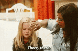 a woman is touching a little girl 's forehead and says " there , there "