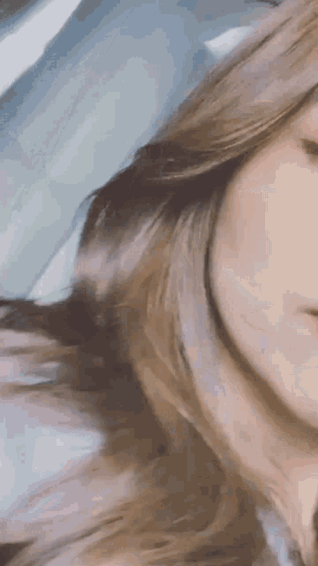 a close up of a woman 's face with long brown hair .