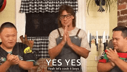 a man in an apron is standing in front of two boys with down syndrome and clapping .