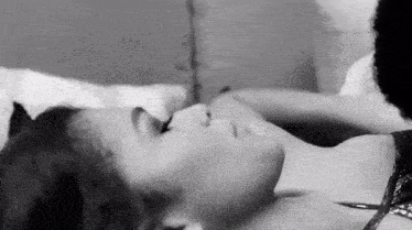 a black and white photo of a woman laying on a bed with a cat .