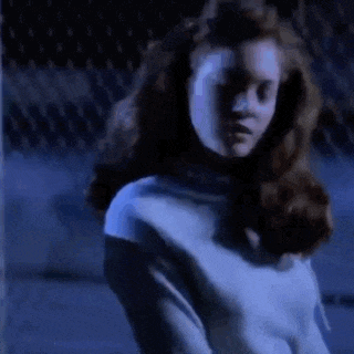 a woman in a blue shirt is standing in the dark .