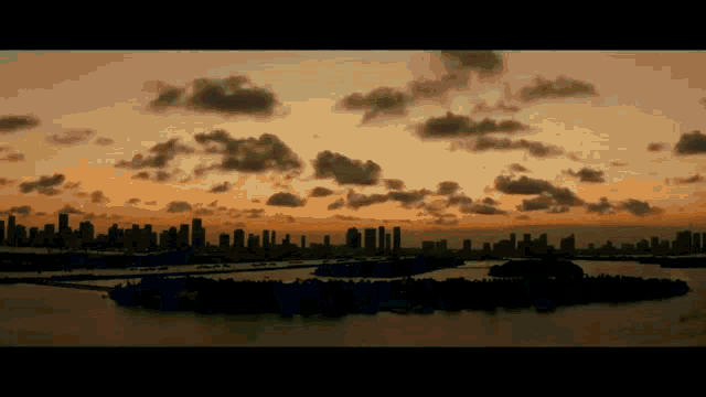 a city skyline is silhouetted against a cloudy sky at sunset