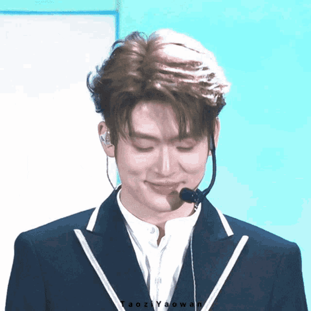 a close up of a man wearing a suit and a microphone with the name aozi yaowan written on the bottom