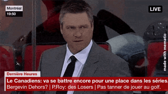 a man in a suit and tie is sitting in the stands watching a hockey game