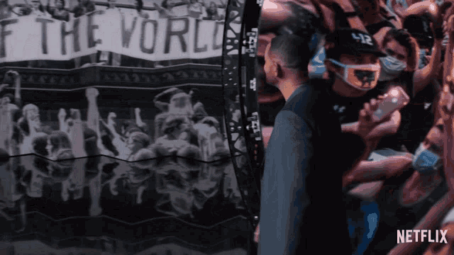 a man stands in front of a crowd with a banner that says " if the world "