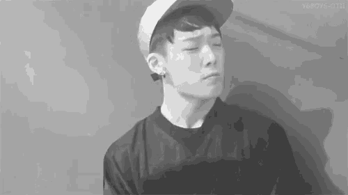 a black and white photo of a young man wearing a baseball cap and a black shirt .