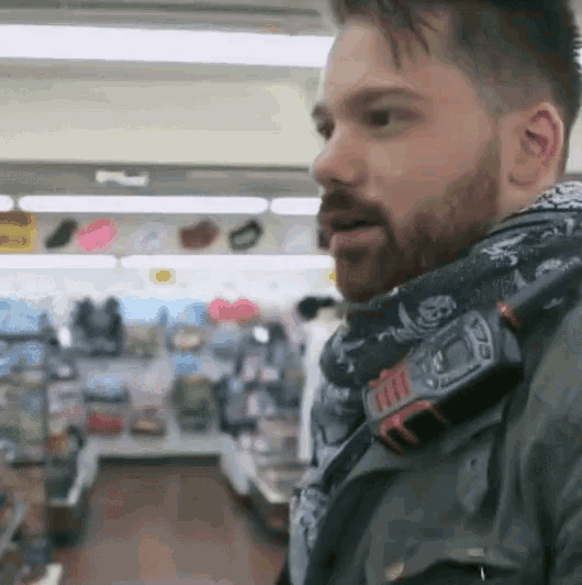 a man wearing a scarf around his neck has a device on his shoulder that says ' tactical '