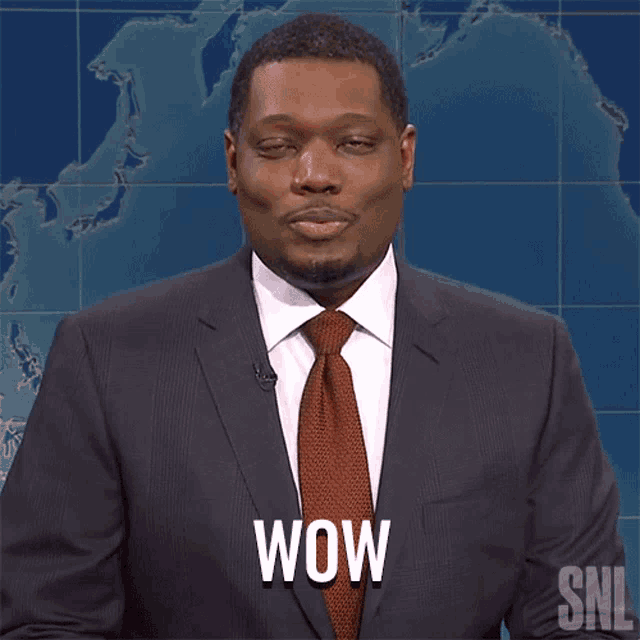 a man in a suit and tie says wow in front of a world map