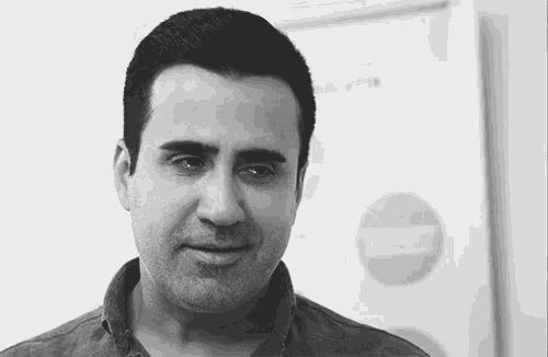 a black and white photo of a man 's face with a poster in the background