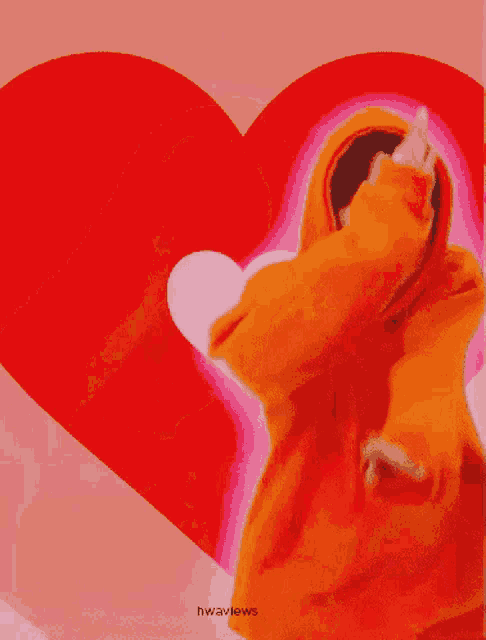 a man in an orange hoodie is making a heart shape