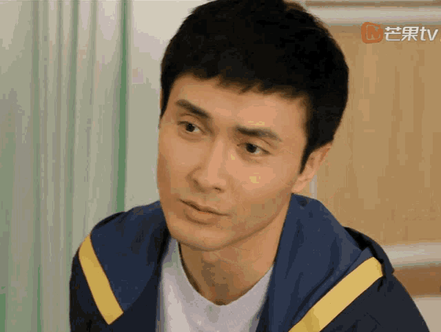 a close up of a man 's face with a chinese tv logo in the background