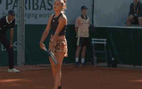 a woman playing tennis in front of a bnp paribas banner