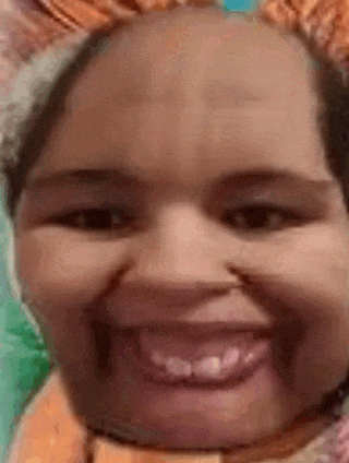 a close up of a woman 's face with a scarf around her neck smiling .